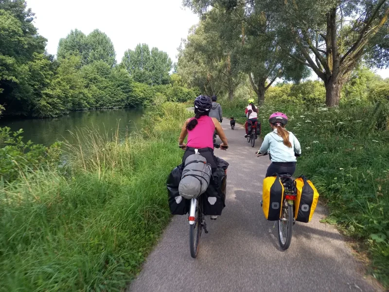 cylotouristes sur un chemin de halage, avec le chien devant eux