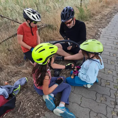 Des enfants et leur père, réparent une chambre à air, assis au bord de la route