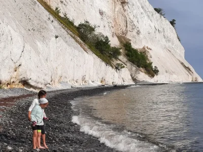 Deux enfants les pieds dans les vagues sous une falaise de craie