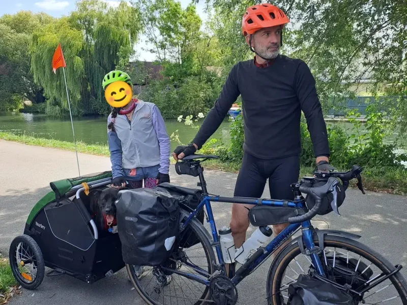 2 cyclistes avec les vélos chargés et la remorque du chien