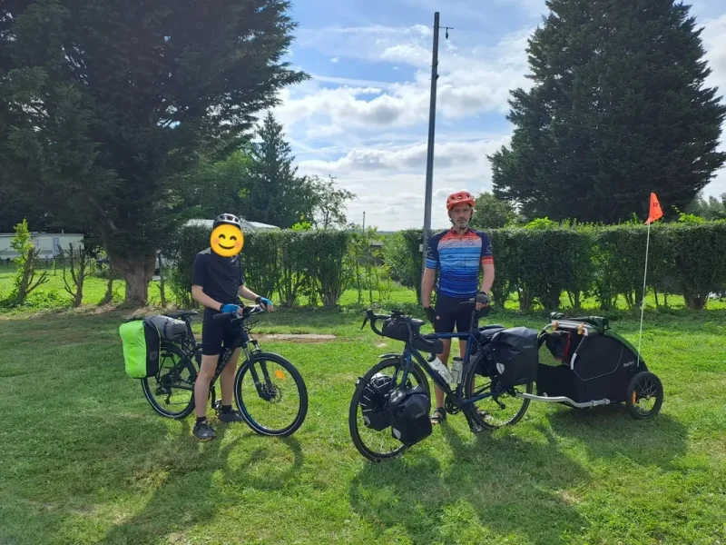 2 cyclistes avec les vélos chargés et la remorque du chien