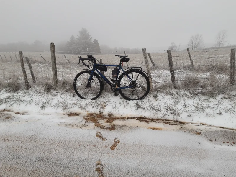 Vélo posé au bord d'une route enneigée