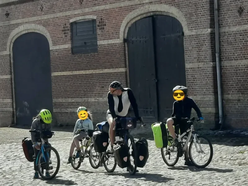 une famille de cyclotouristes dans une rue pavée avec les vélos chargés