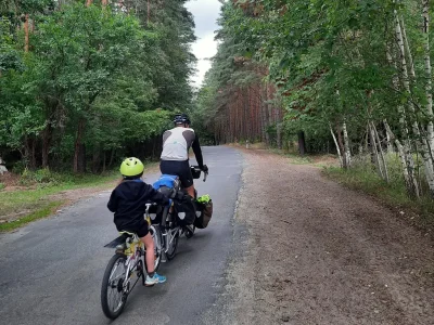 Papa et sa fille pédalent sur une route forestière