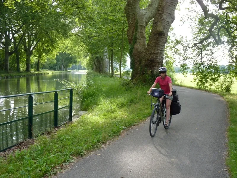 Une femme pédale sur une voie verte le long d'un canal