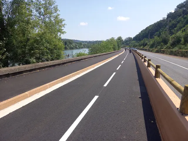 Piste cyclable toute neuve, large et confortable, séparée de la circulation par un muret en béton surmonté d'une barrière en bois.